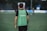 man in green and black adidas tank top and black pants standing on green grass field