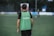 man in green and black adidas tank top and black pants standing on green grass field