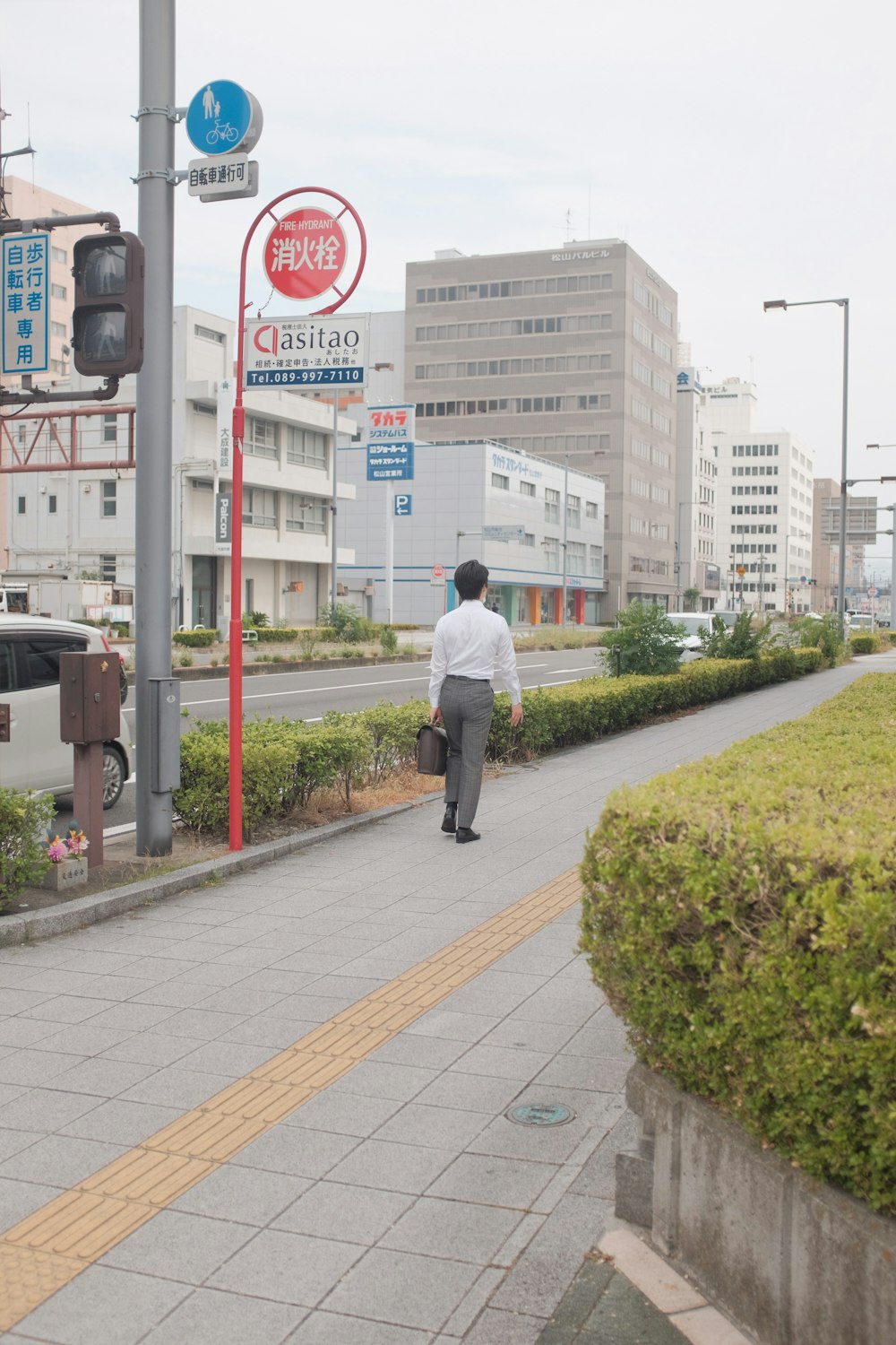 man in white dress shirt and black pants walking on sidewalk during daytime