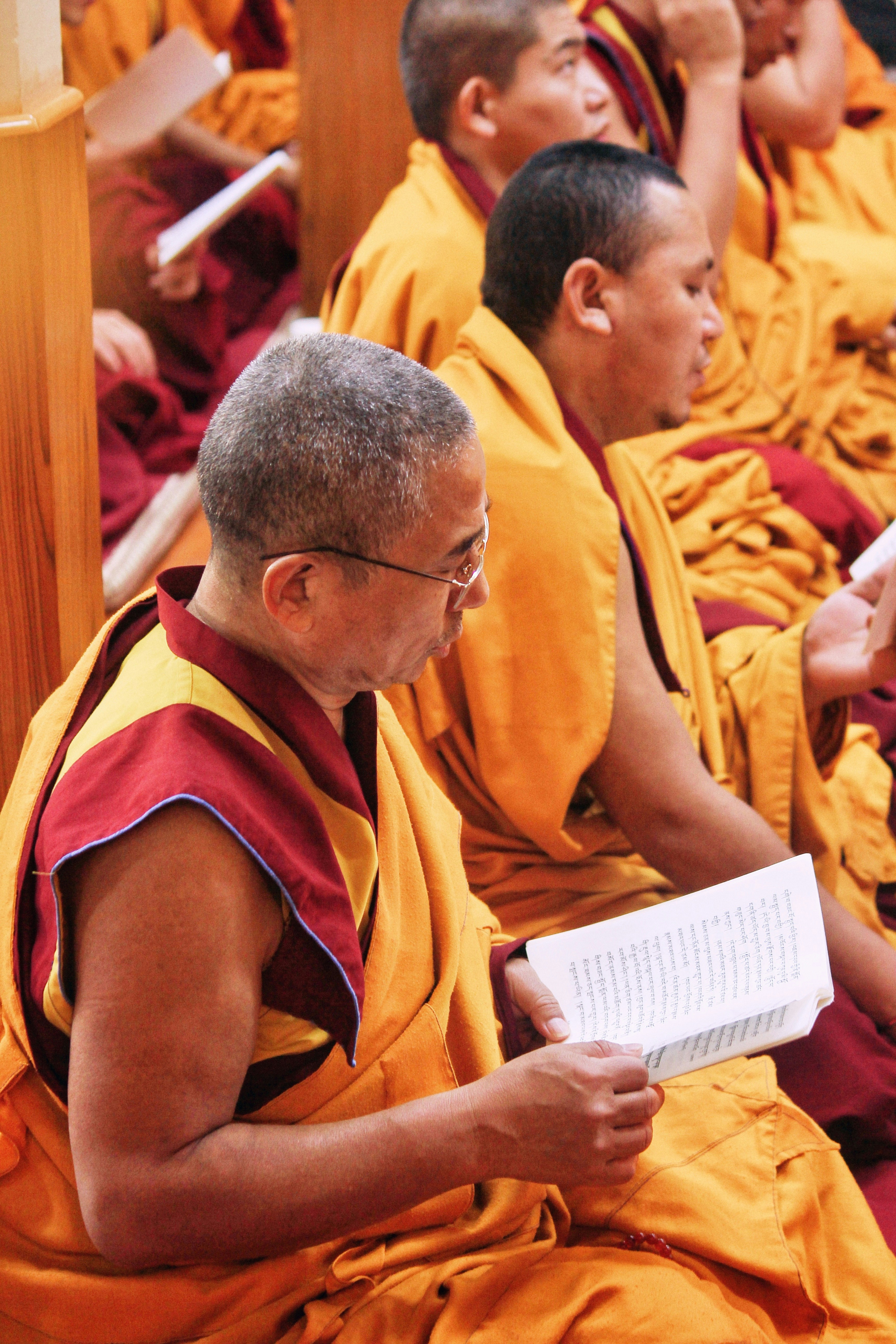 Buddhist monks in saffron robes reading from books in a temple