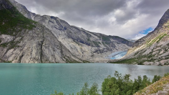 green and brown mountain beside body of water during daytime in Nigardsbreen Norway