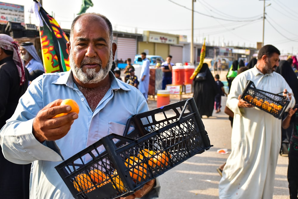 man in blue polo shirt holding orange fruit