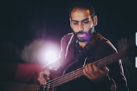 Alexis focused on his bass guitar, shadows playing across his face