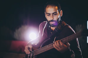 Artistic frame of a bassist playing with shadows casting dramatic patterns on the wall.