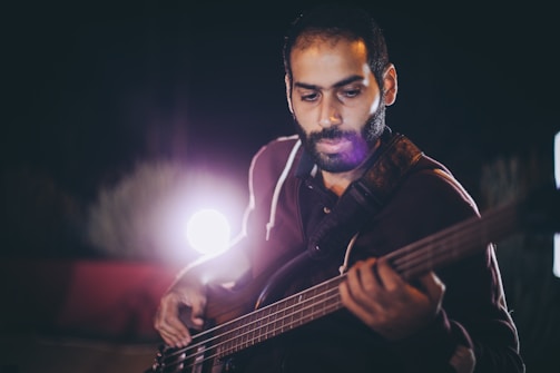 Christoph Milton deeply focused while playing bass under moody stage lights.