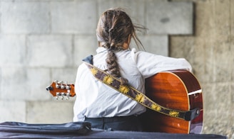 woman in white long sleeve shirt playing brown acoustic guitar