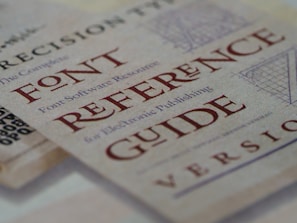A close-up view of a document featuring the text 'FONT REFERENCE GUIDE' in large, bold, red letters. The background includes a subtle, textured pattern along with smaller text that appears to relate to typography.