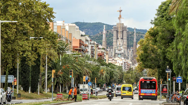 A bustling street in Ambato with buses and cyclists sharing the road during rush hour