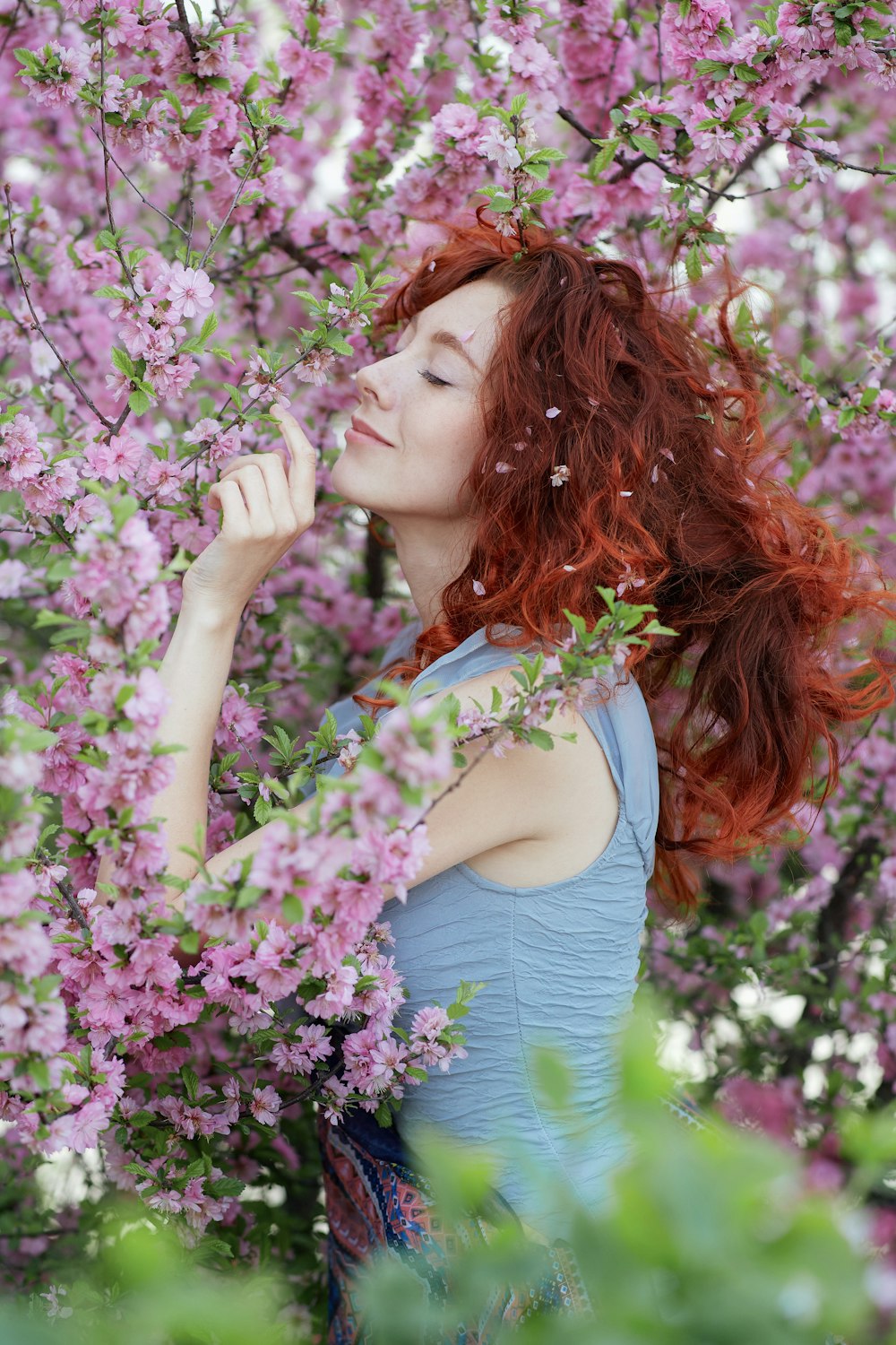 mulher na regata azul-petróleo que segura as flores roxas