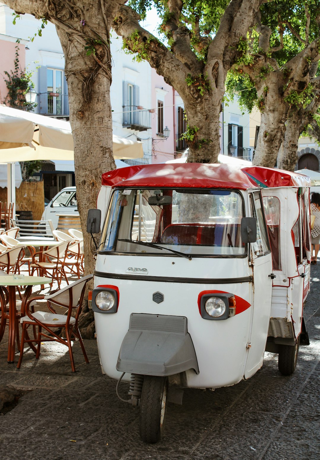 white and red volkswagen t-2 parked near brown wooden table and chairs