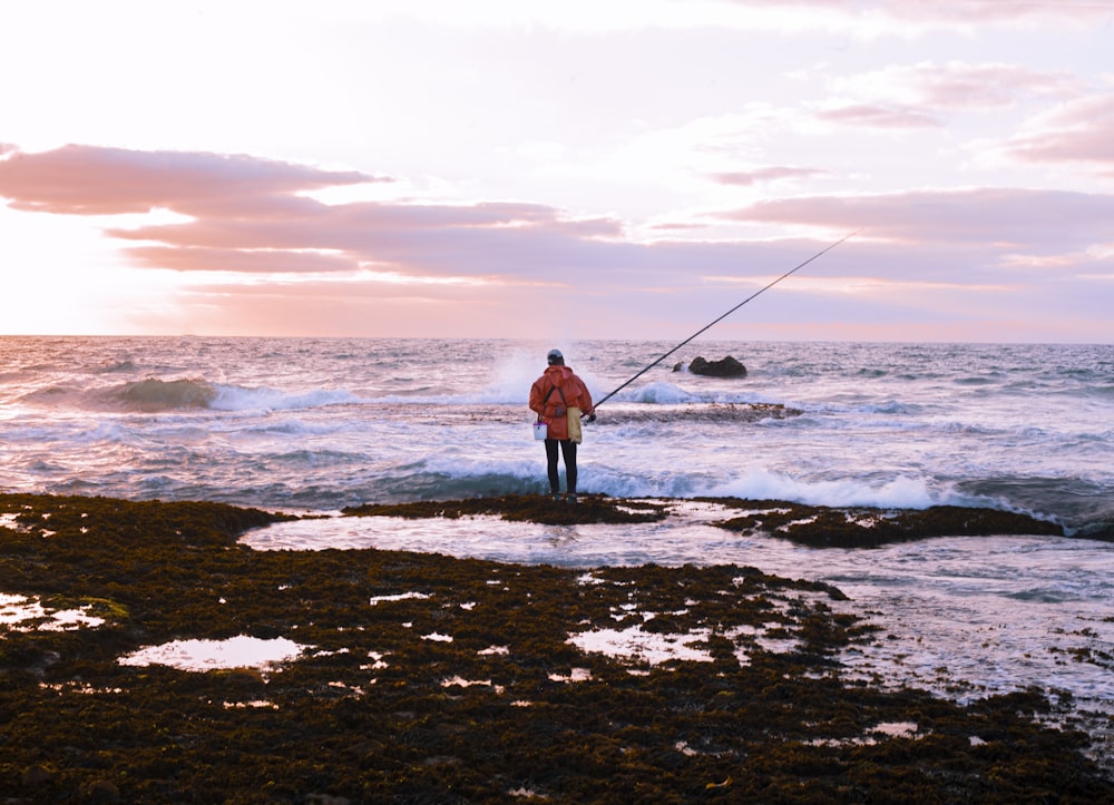 man in black shirt and black pants fishing on sea during daytime