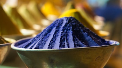 Close-up of colorful powdered food additives being mixed in a stainless steel bowl.