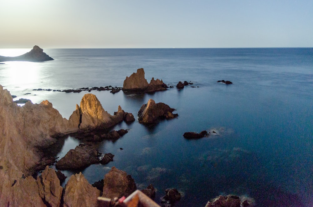 brown rocks on blue sea under white sky during daytime