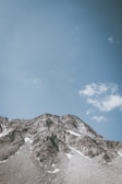 A mountain peak viewed from a rocky ledge under a clear blue sky.