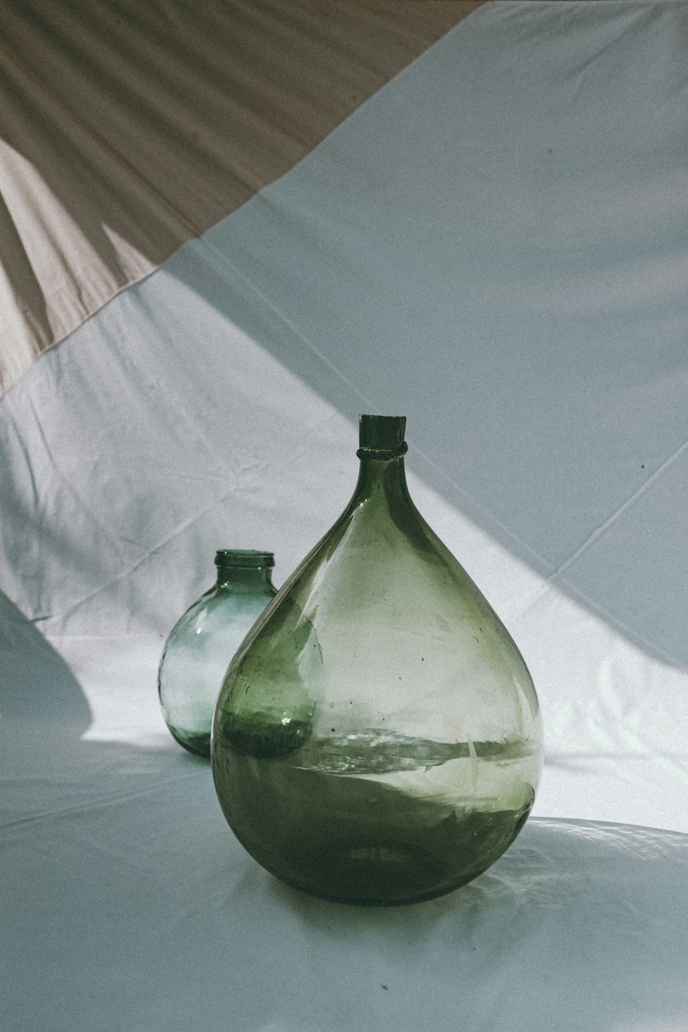 green glass bottle on white textile