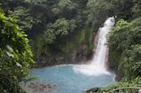 Crystal-clear waterfall surrounded by vibrant jungle greenery.