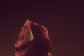 A polished ruby with a rich red hue resting on a wooden surface.