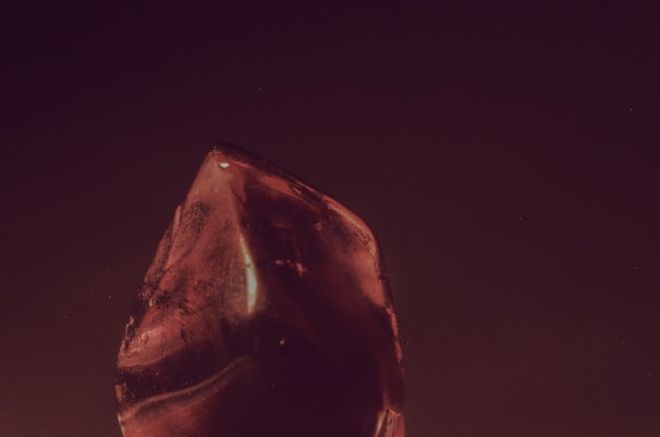 A polished ruby with a rich red hue resting on a wooden surface.