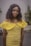 A model wearing a vibrant yellow summer dress in a sunny outdoor setting.