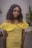 A model wearing a vibrant yellow summer dress in a sunny outdoor setting.