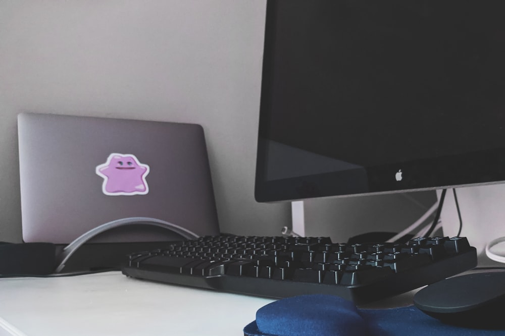 silver imac and black computer keyboard on white table