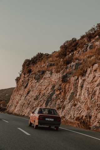 A classic American road trip scene with a vintage car on an open highway
