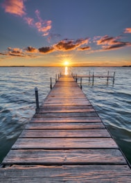 brown wooden dock on sea during sunset