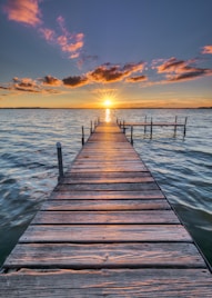 brown wooden dock on sea during sunset