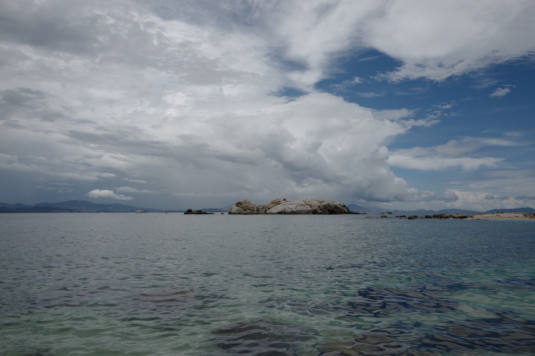 brown rock formation on sea under white clouds during daytime