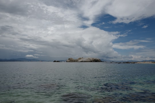 brown rock formation on sea under white clouds during daytime in Sanya China