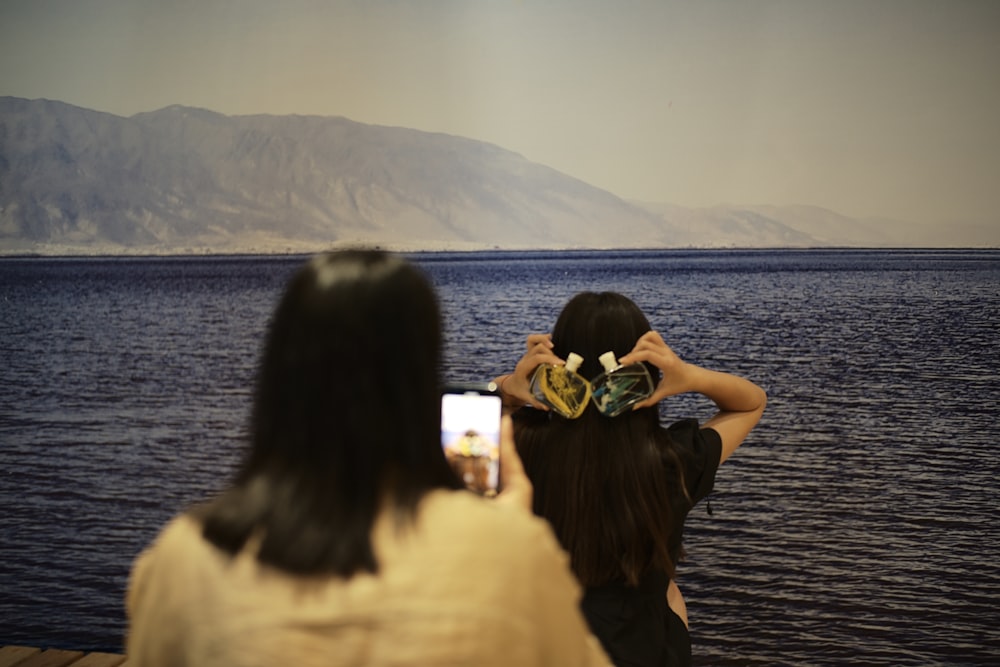 3 women sitting on wooden dock during daytime