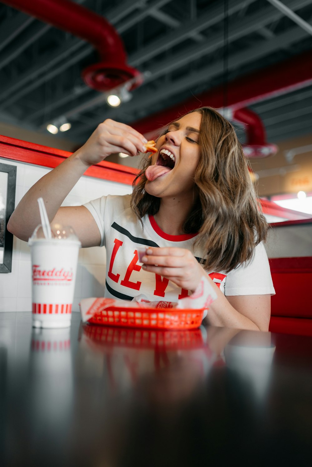 femme en blanc et rouge débardeur manger