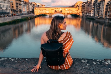 photography poses for women,how to photograph sunsets; woman in black and orange striped shirt and black leather sling bag standing on gray concrete