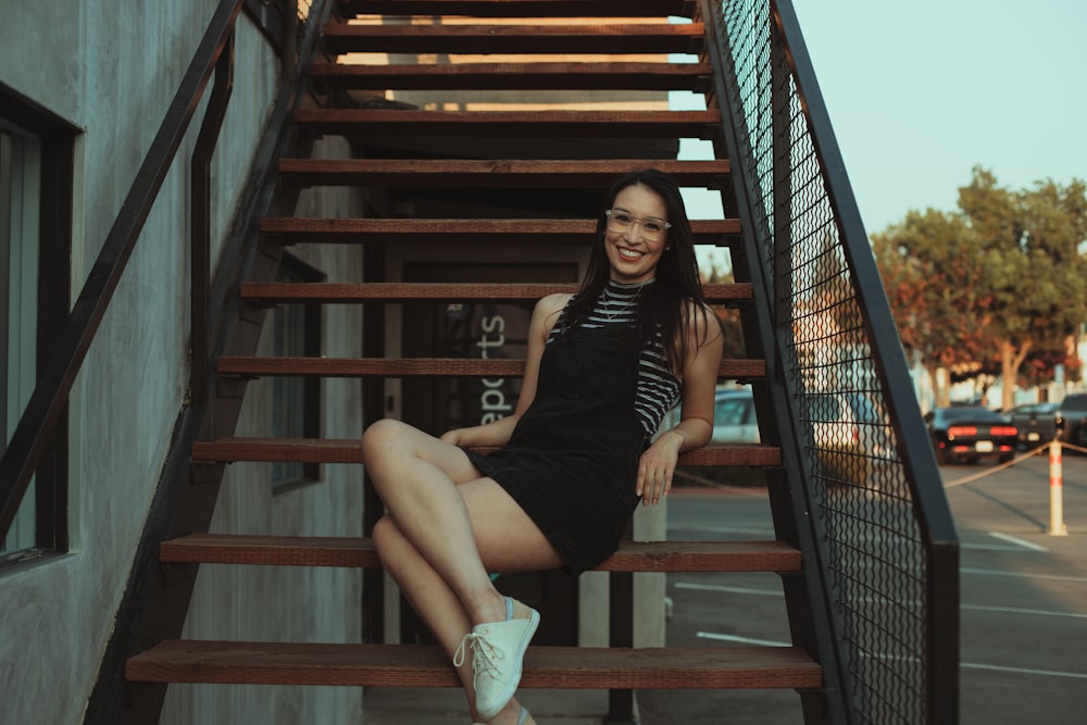 woman in black tank top sitting on brown wooden staircase