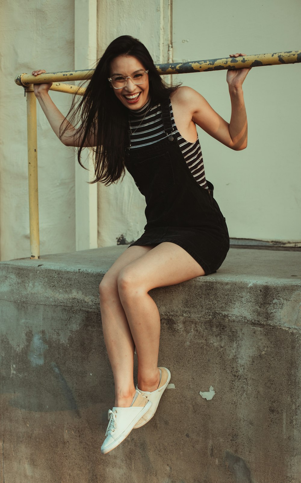 woman in black tank top and black shorts sitting on concrete wall