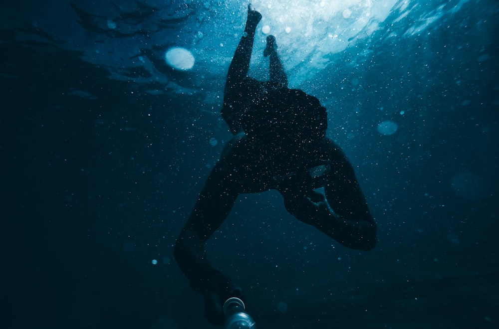 Person im schwarzen Taucheranzug unter Wasser