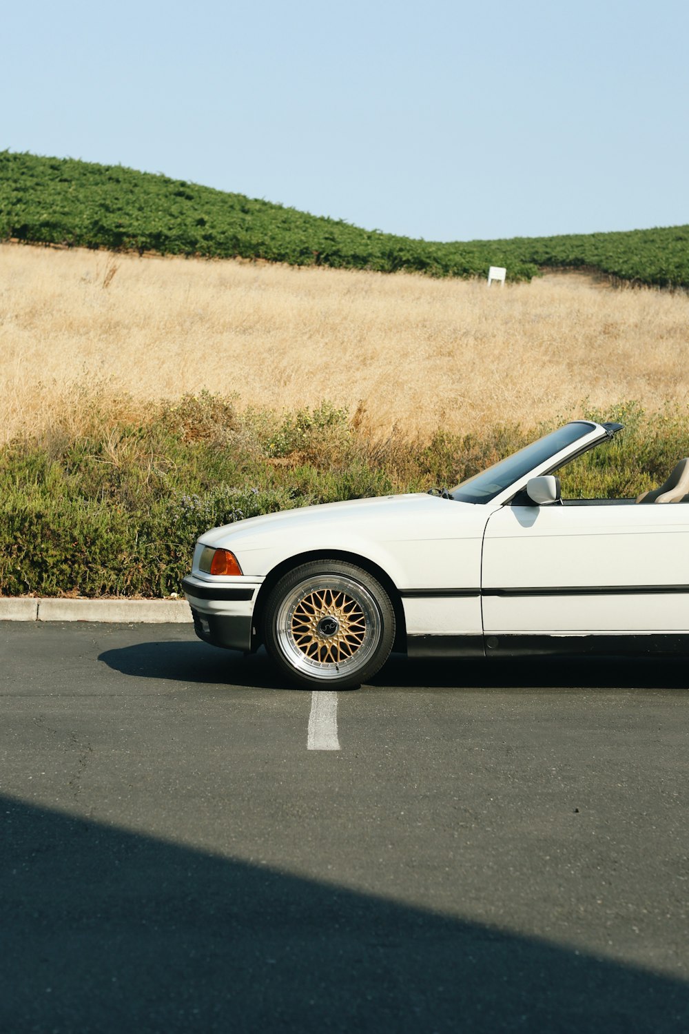 white coupe on gray asphalt road during daytime