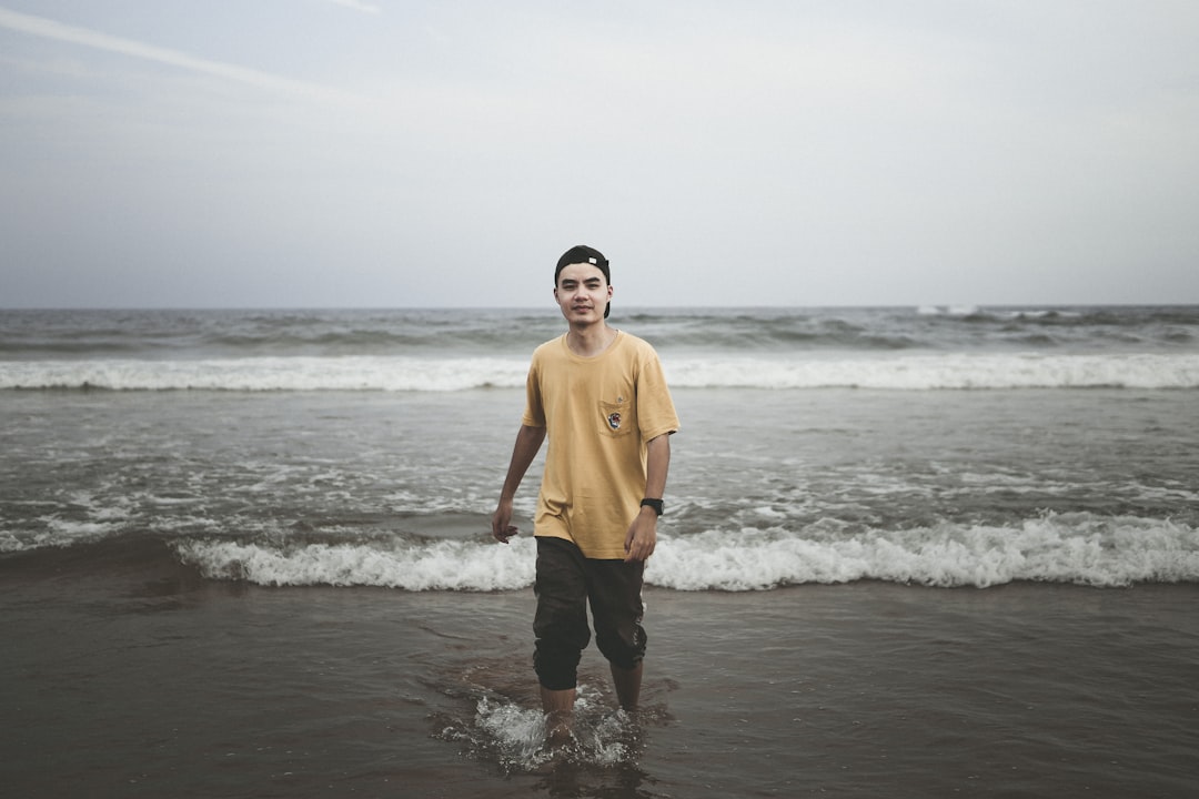 man in brown long sleeve shirt and black pants standing on beach during daytime