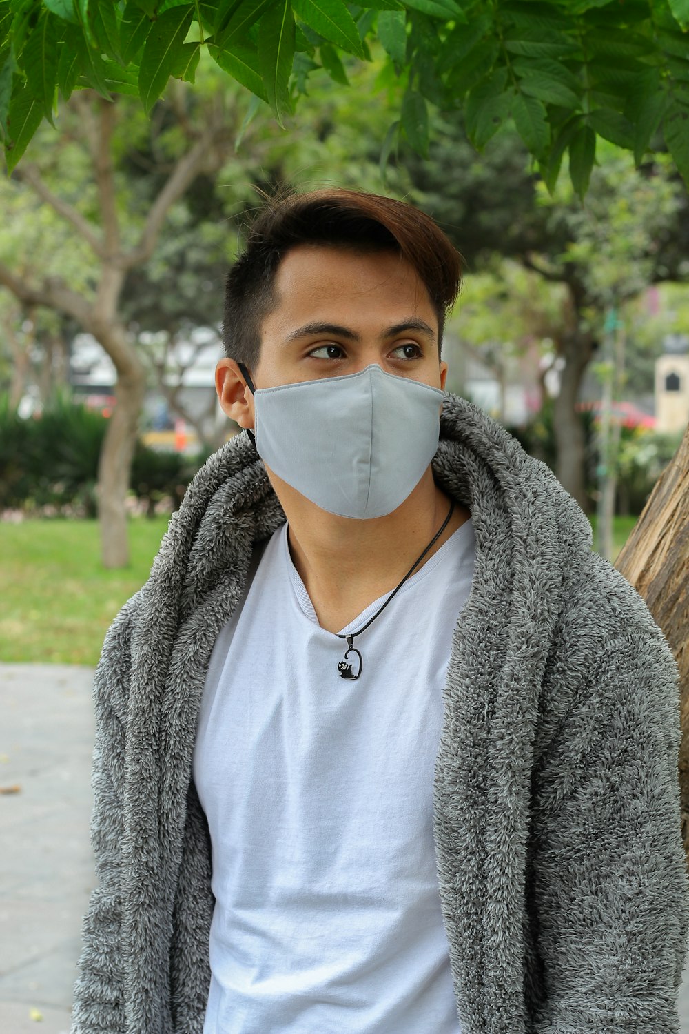 woman in gray cardigan wearing white face mask