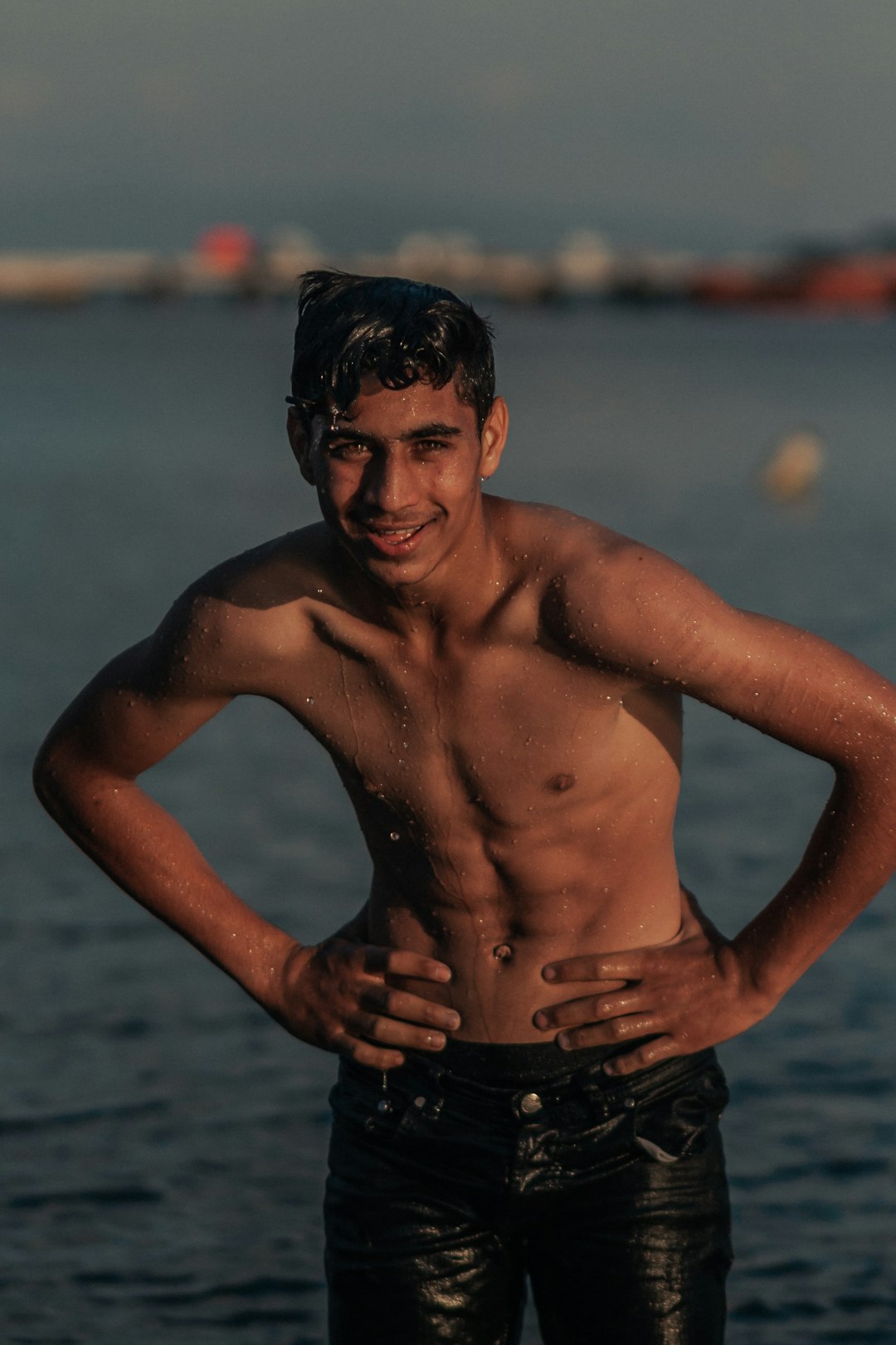 topless man in black shorts standing on water during daytime