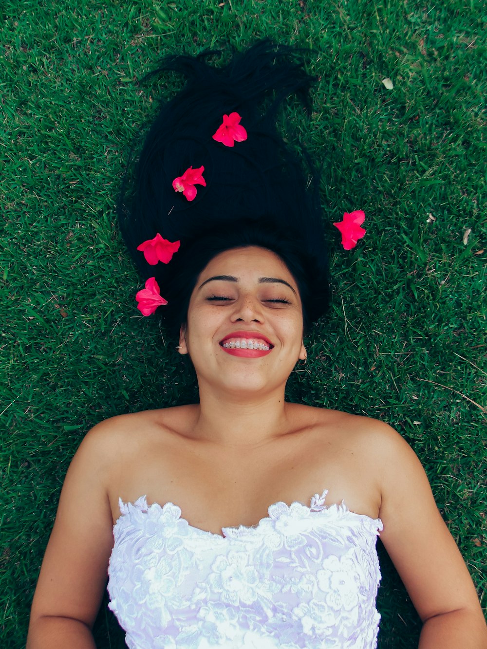 woman in white floral dress lying on green grass