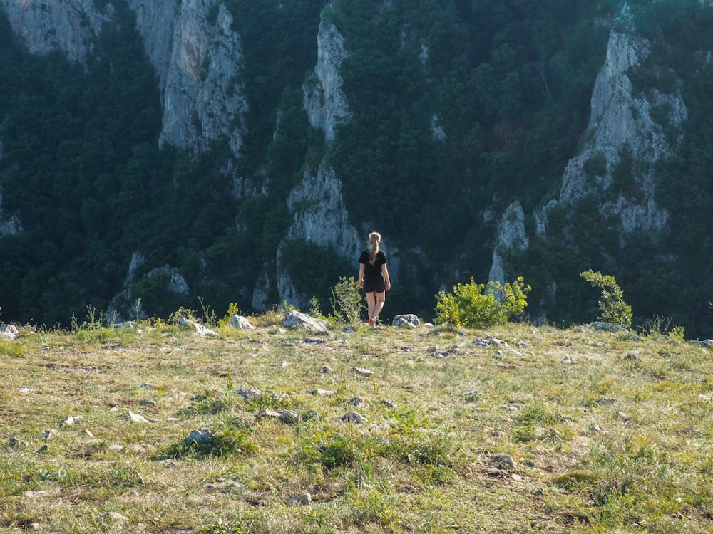 femme en débardeur noir et short marron debout sur le champ d’herbe verte pendant la journée