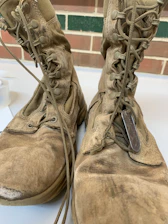 A close-up of rugged military boots resting on a worn wooden crate.
