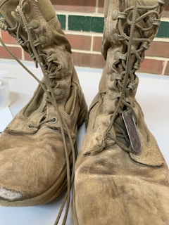 An old pair of worn combat boots resting on the ground.