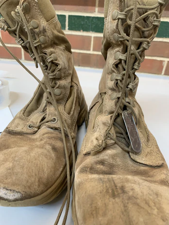 A close-up of rugged military boots resting on a worn wooden crate.