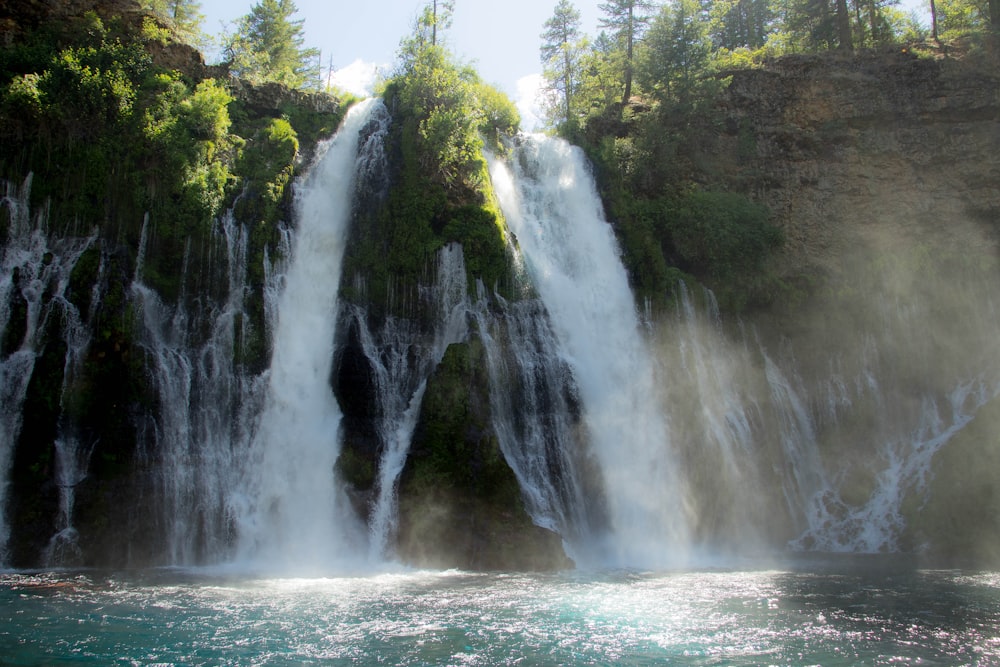 waterfalls in the middle of green trees during daytime