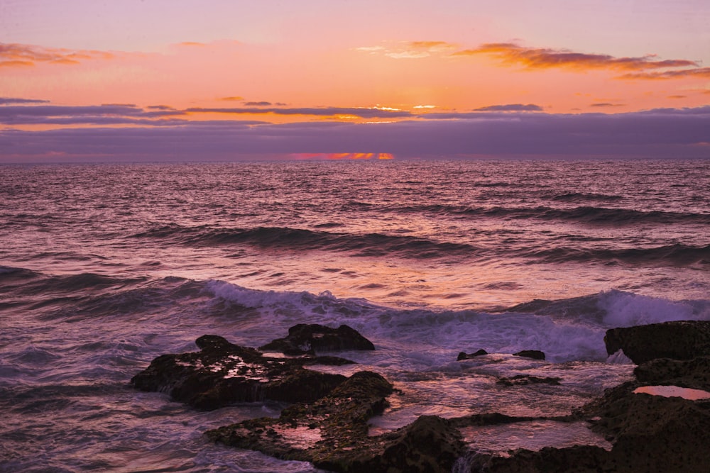 ocean waves crashing on rocks during sunset