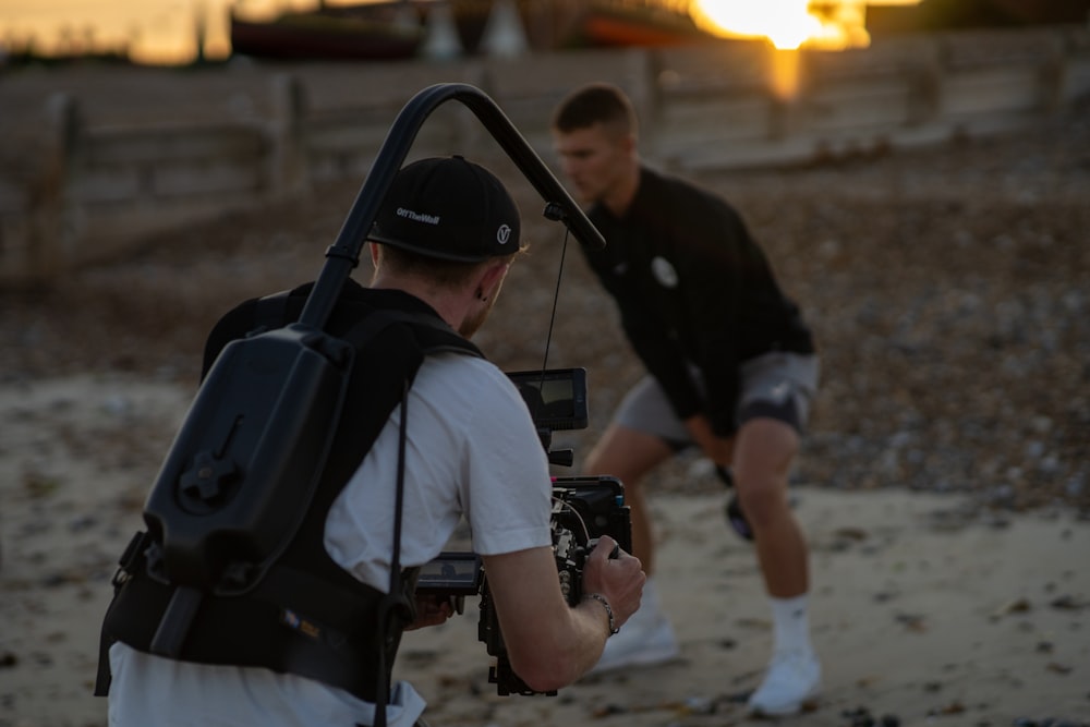 man in white t-shirt and black backpack holding black dslr camera