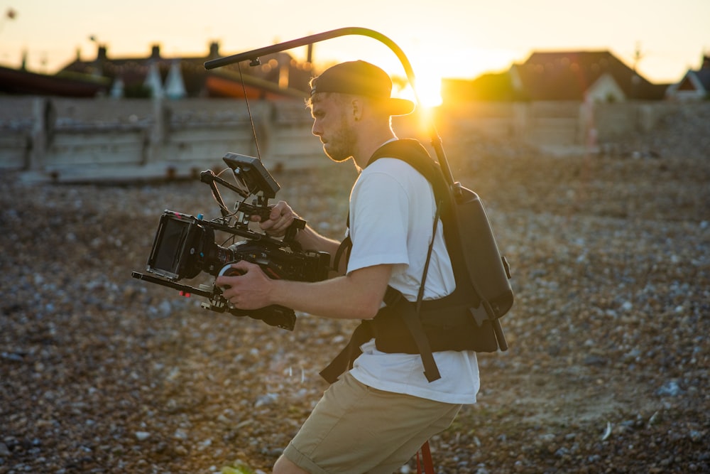 man in white t-shirt holding black video camera