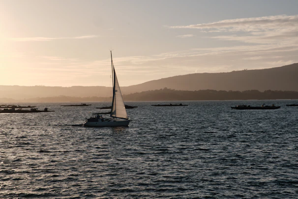 A small private boat gliding through calm blue waters near lush green islands at sunset.